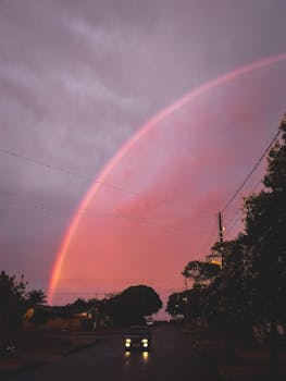 一条令人惊叹的彩虹划过安静的街道，映衬在色彩缤纷的日落之中