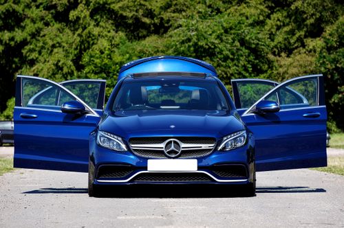 Free Elegant blue sports car with open doors on a sunlit rural road. Perfect for automotive enthusiasts. Stock Photo