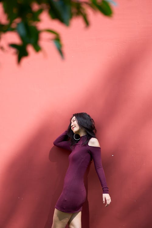 Woman in Purple Cold Shoulder Dress Standing by a Pink Wall