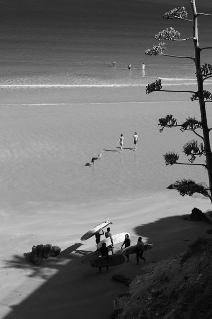 Black and white photo of surfers and beachgoers on Imsouane beach, Morocco.