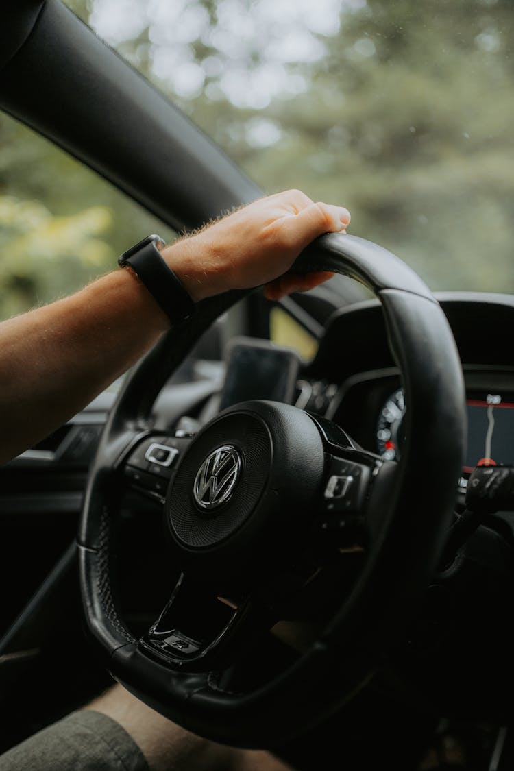 Man Holding A Steering Wheel Of A Volkswagen Car With One Hand