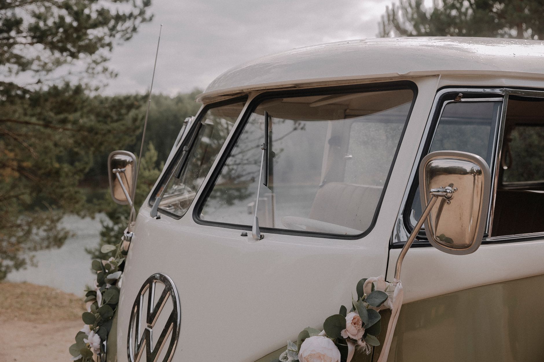 A classic Volkswagen van with floral decorations parked in a scenic outdoor setting.