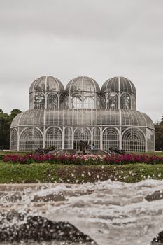 郁郁葱葱的花园中，一座优雅的玻璃温室设有圆顶，展示了植物建筑