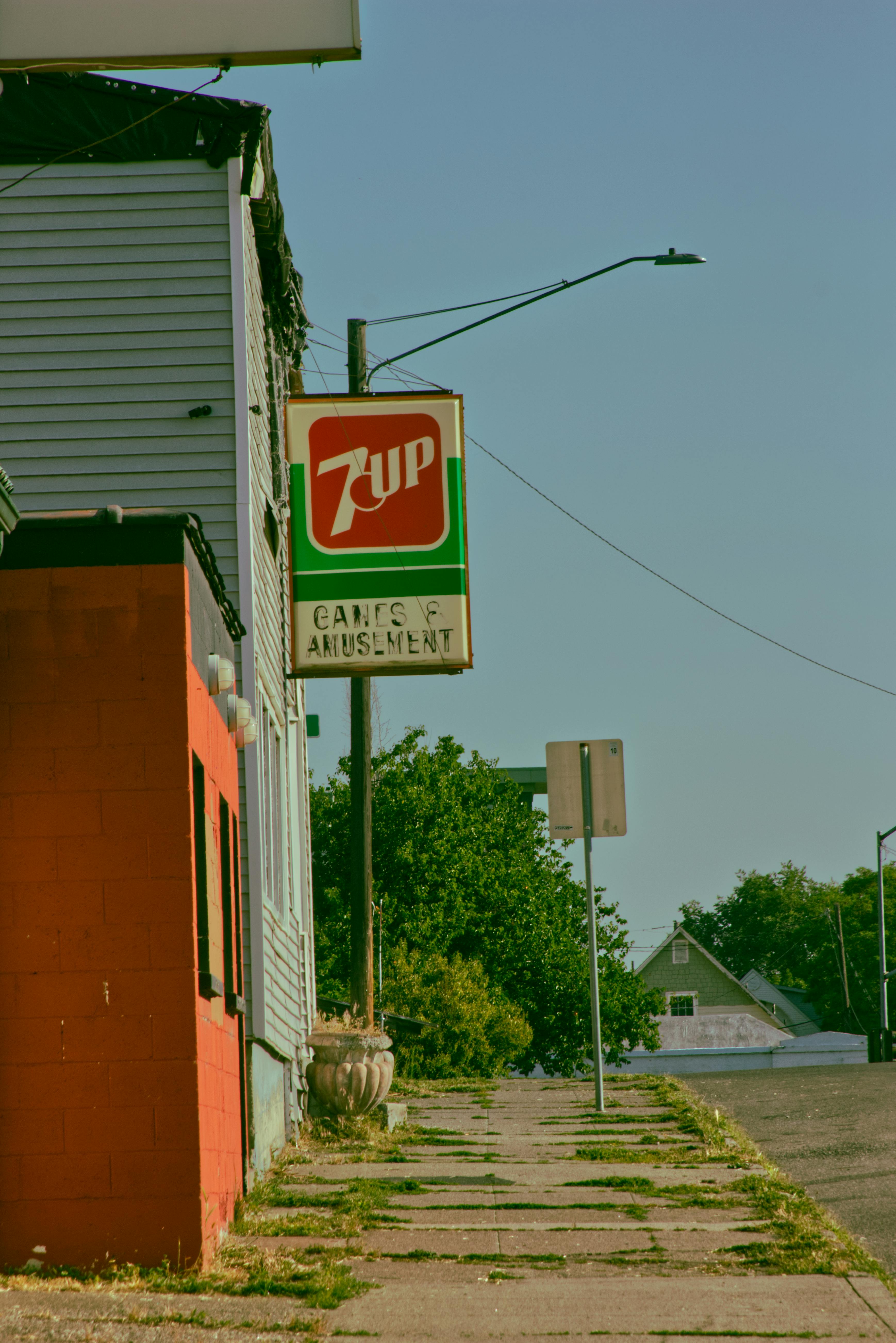 Street view of an urban area featuring a vintage 7 Up sign and sidewalk.
