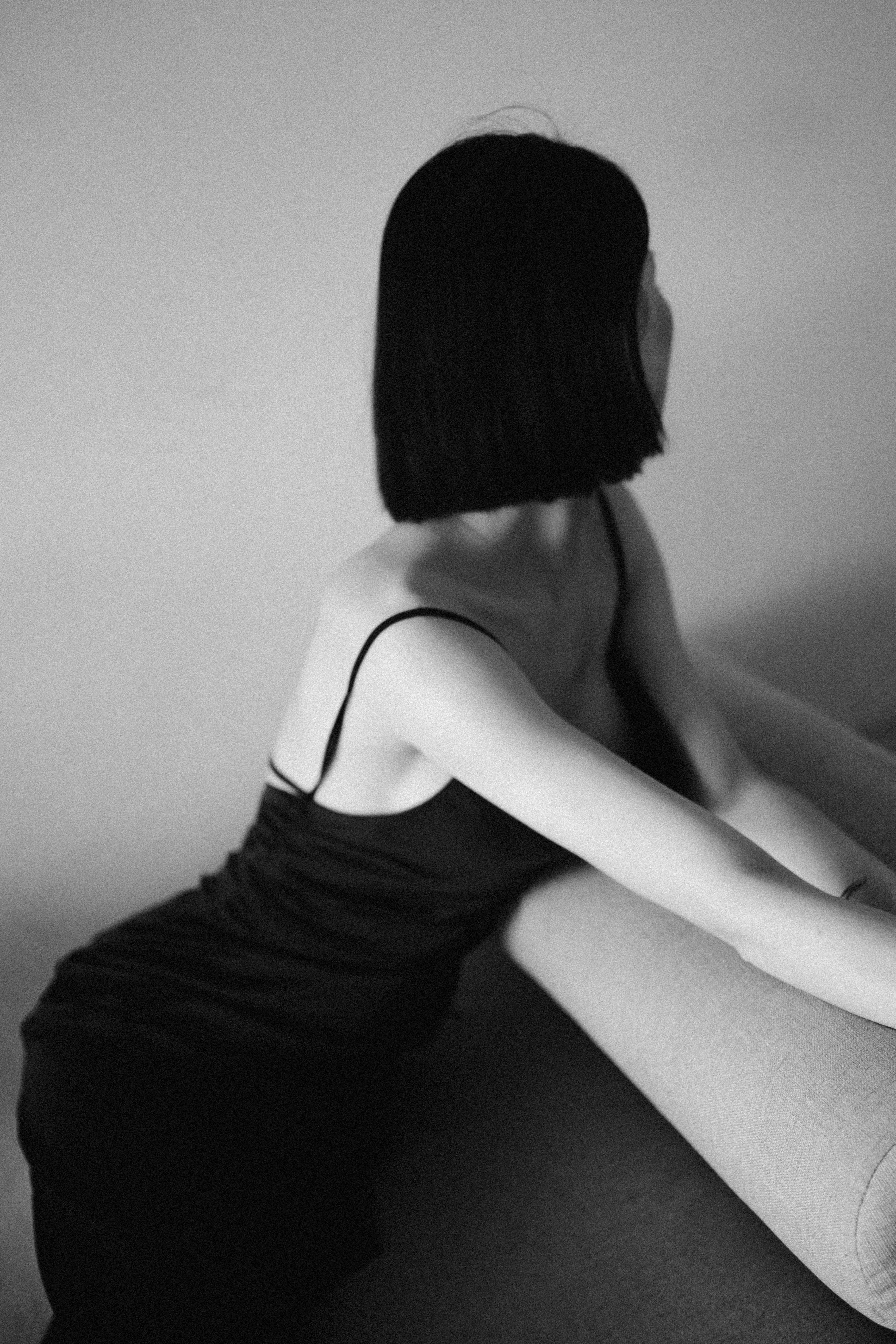 Artistic black and white portrait of a woman in a stylish dress posing elegantly indoors.