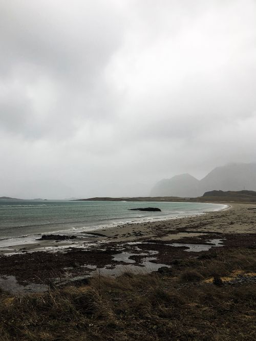Free A deserted beach under a dark, moody sky with rain clouds. Stock Photo