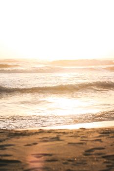 Gentle ocean waves at sunset on a tranquil sandy beach with a golden glow.