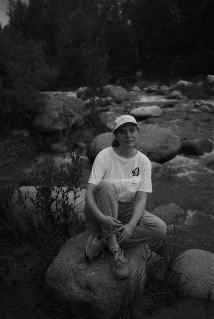 Woman In Cap Sitting On Rock