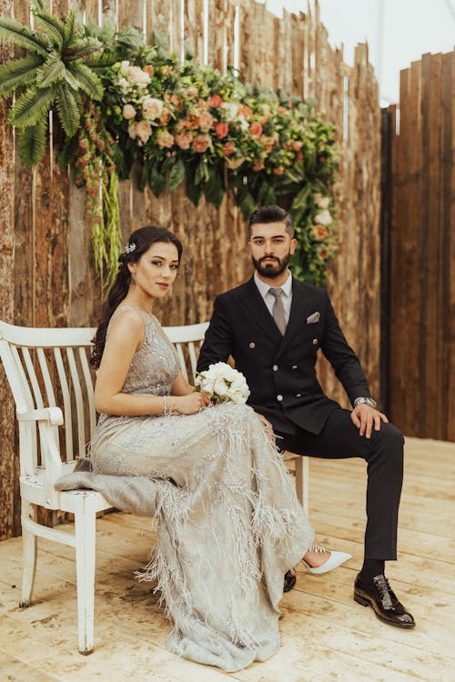 Elegant Bride and Groom Sitting on White Bench