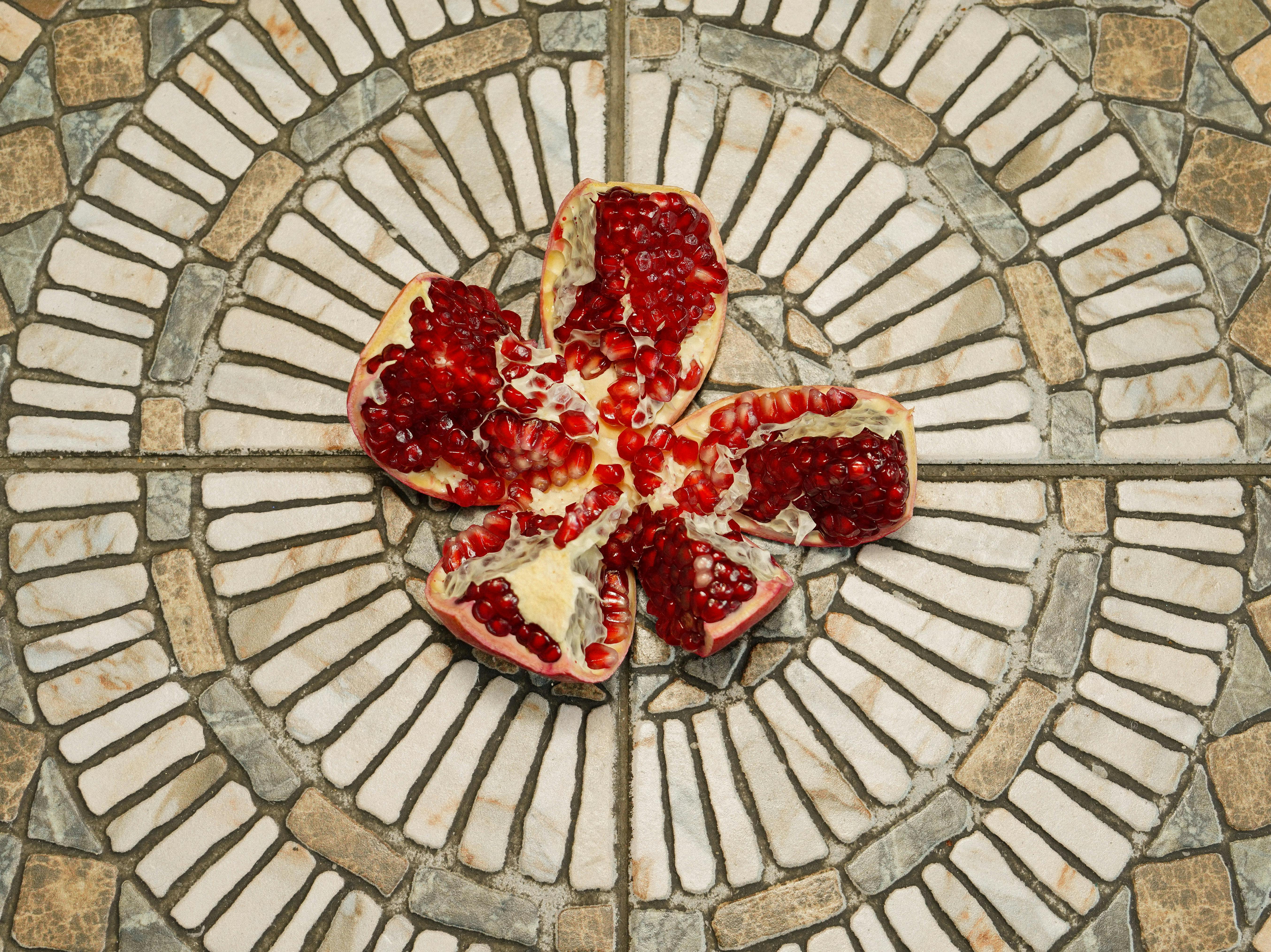 A vibrant, open pomegranate arranged on a circular stone mosaic for a striking visual effect.