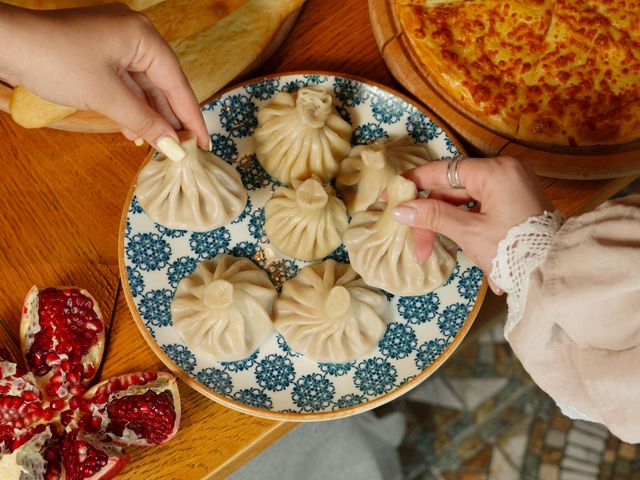 Close-up of Georgian dumplings khinkali with bread and pomegranate on a wooden table.
