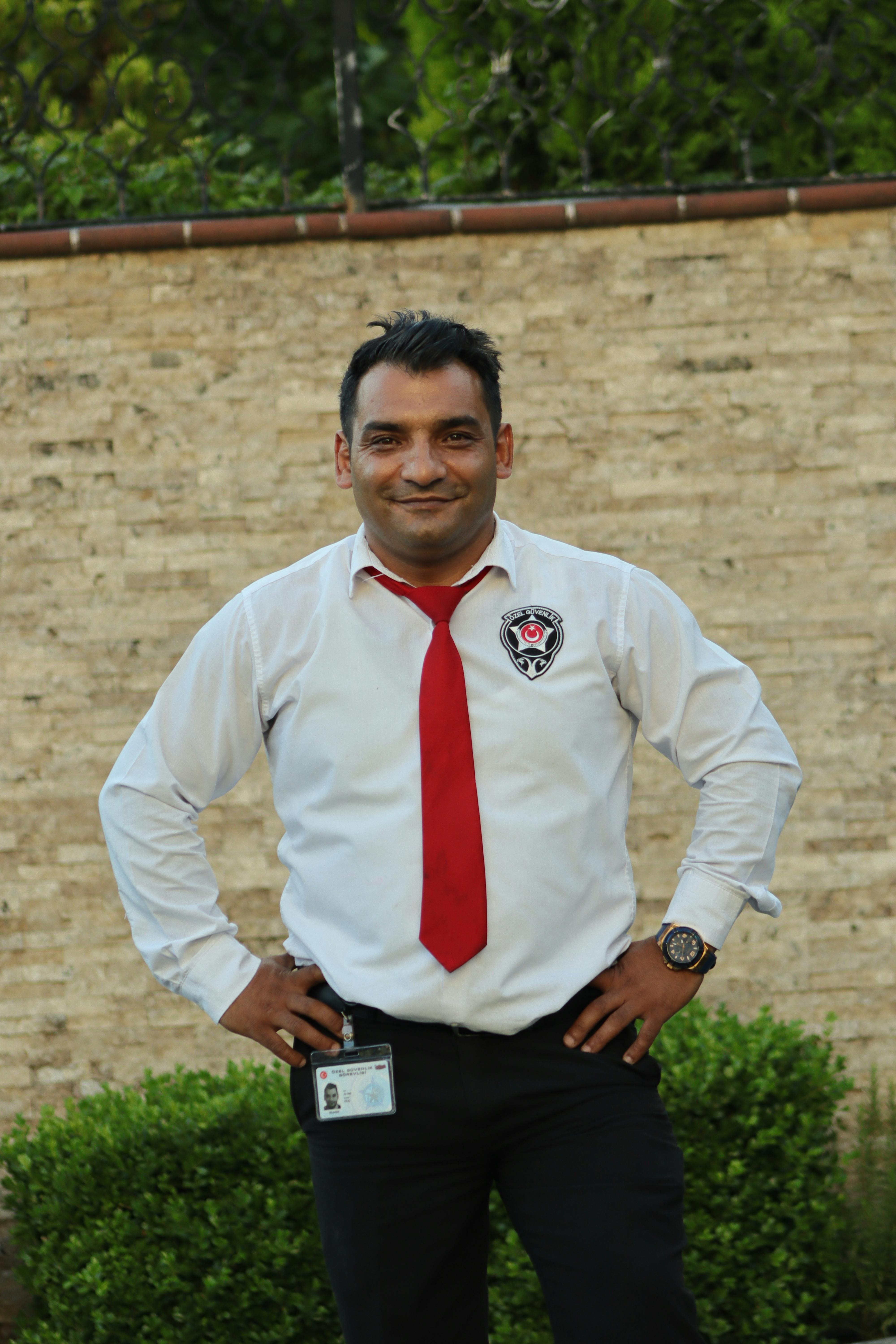 Smiling security guard posing confidently with hands on hips outdoors.