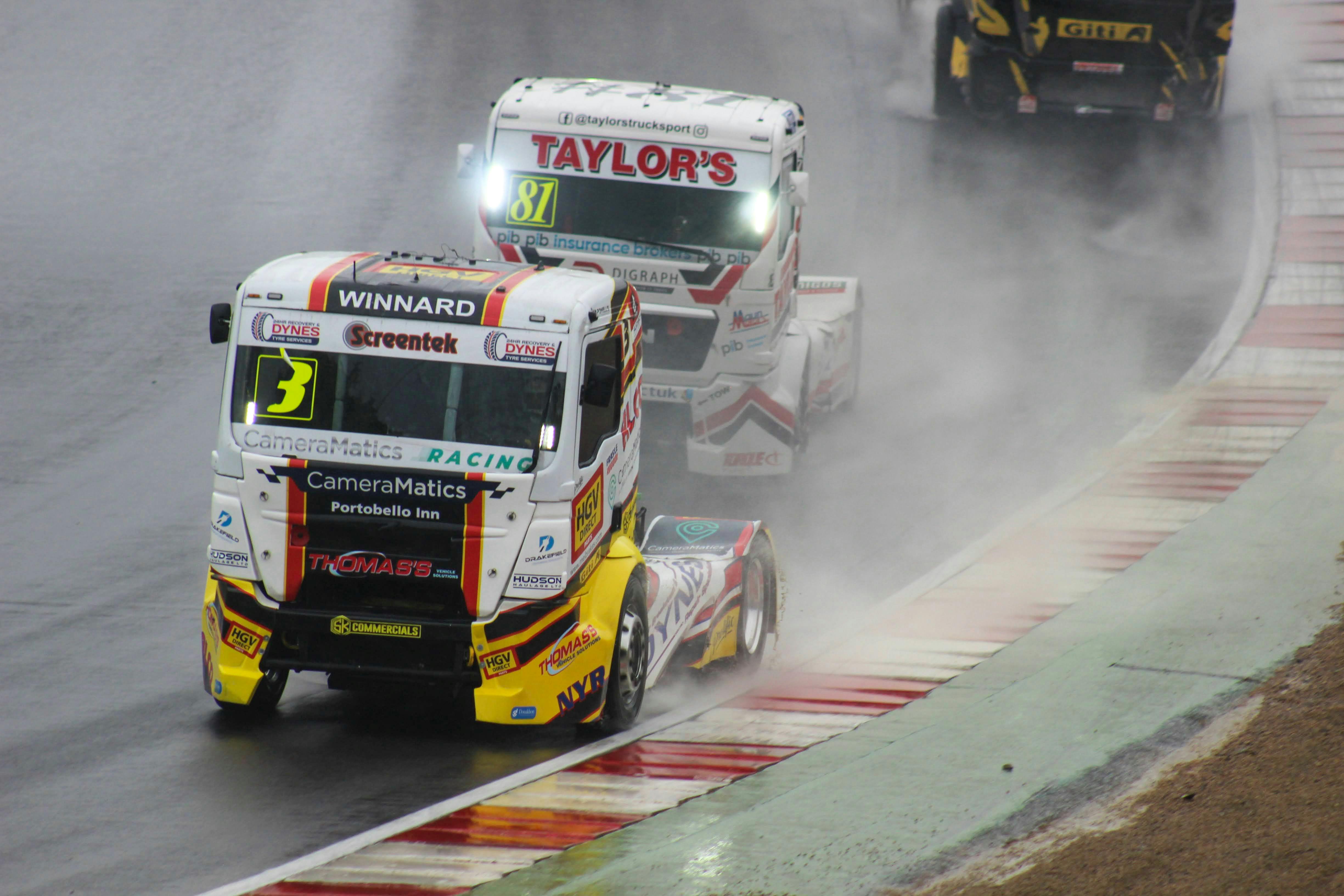 Exciting truck racing action on a rain-soaked track showcasing speed and skill.