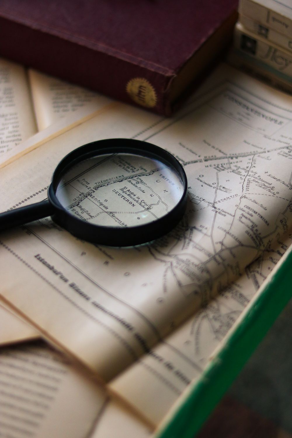 A Magnifying Glass Lying on a Vintage Book with a Map · Free Stock Photo