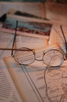 Retro eyeglasses resting on an open historical map and vintage books, evoking a sense of discovery.