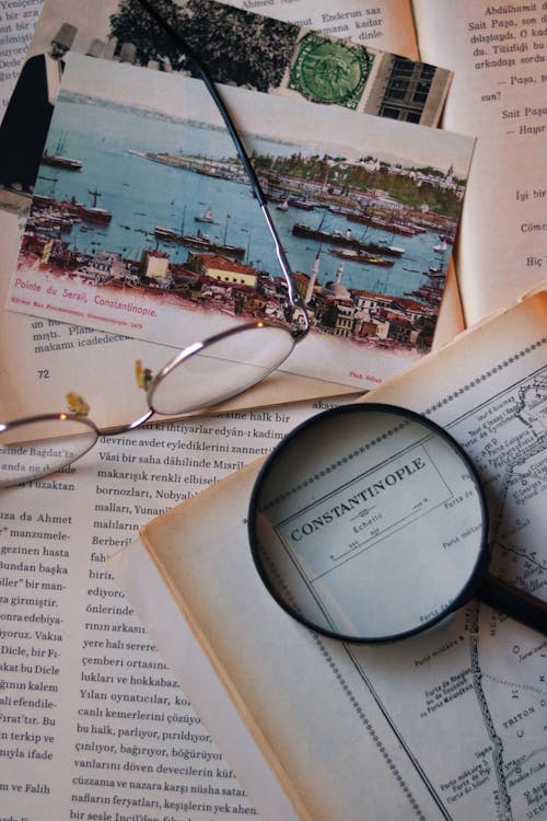 A Magnifying Glass and Eyeglasses Lying on a Vintage Book with a Map 