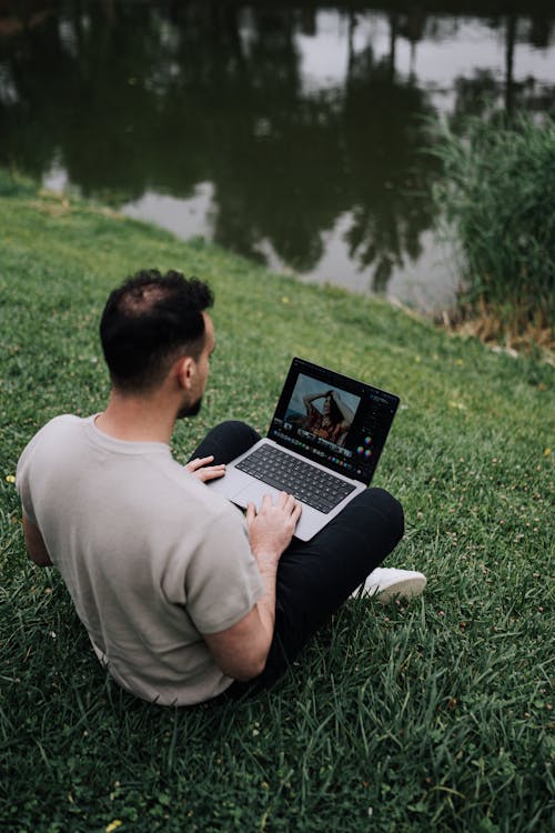 Man Sitting with Laptop near Water