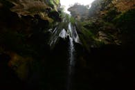 瀑布从岩石悬崖倾泻而下，四周环绕着郁郁葱葱的树叶