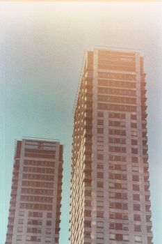 Two high-rise apartment buildings with a vintage grainy effect under a clear sky.