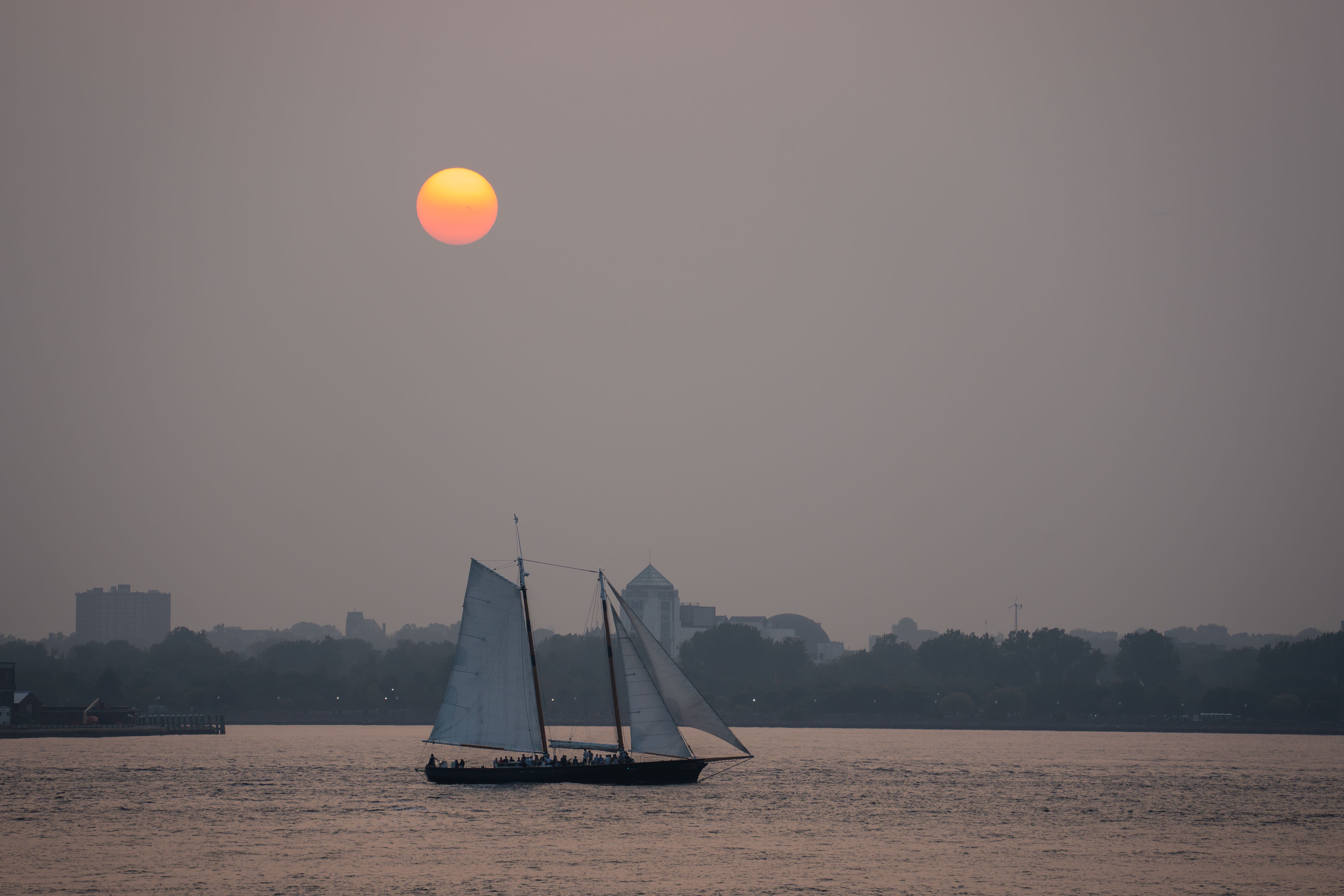 Unforgettable 2.5-hour Guided Sailboat Tour Review: Sailing Past the Brooklyn Bridge and Statue of Liberty Review 2026 - Serene view of a sailboat silhouetted against the sunset on a New York City waterway.