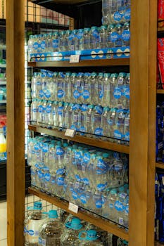 Bottled water neatly arranged on supermarket shelves displaying consumer goods.