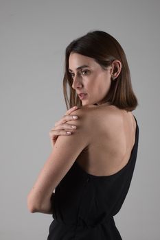 Stylish studio portrait of a young woman in a black dress, showcasing elegance.