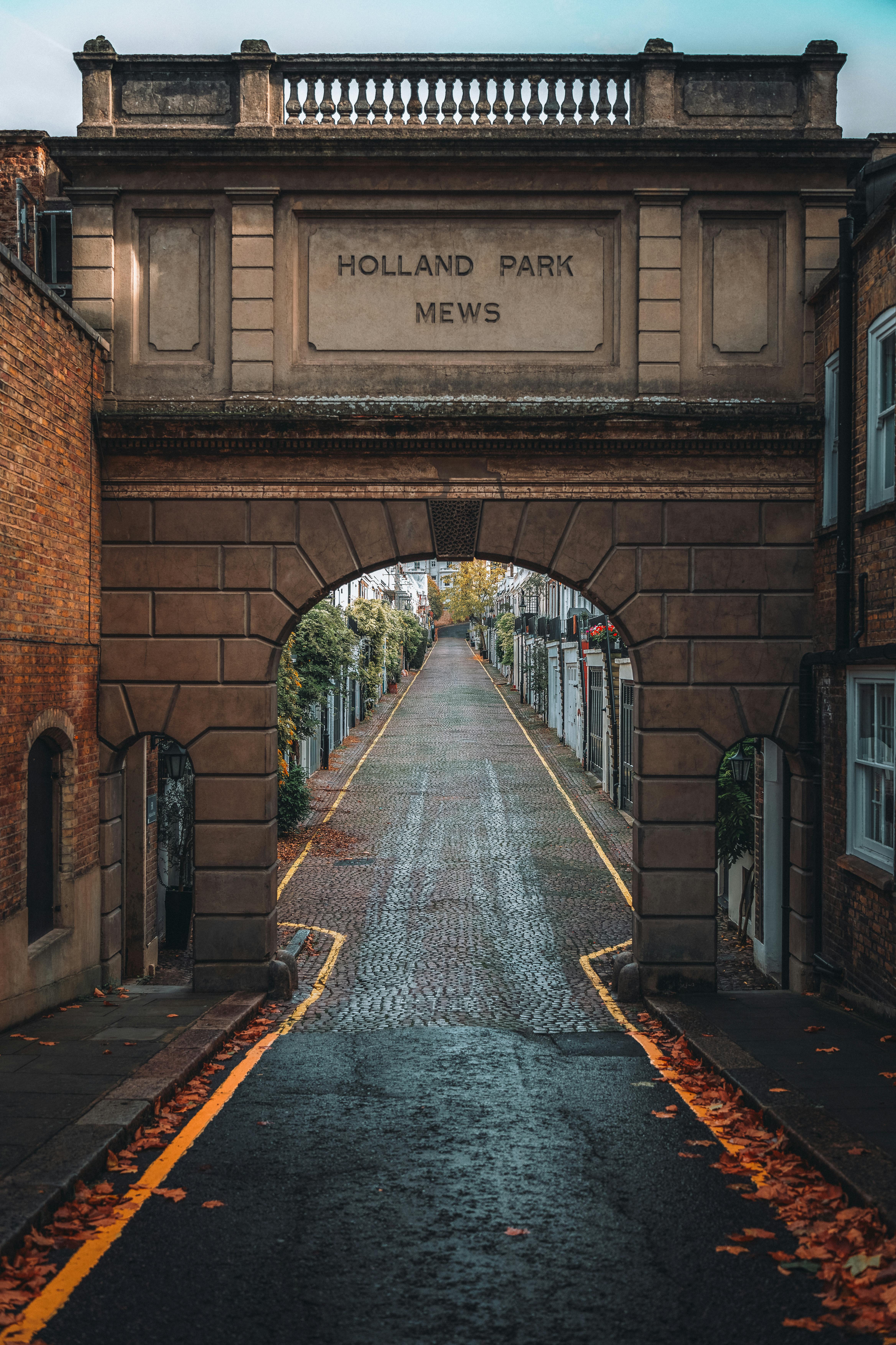 View of Holland Park Mews archway in London, showcasing historic architecture and cobblestone street.