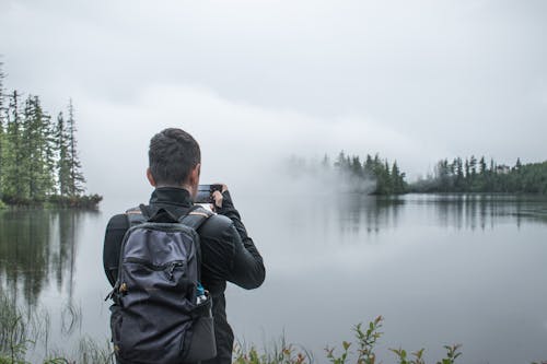 Man Taking a Picture of a Lake in Fog 