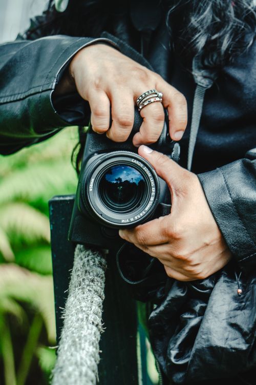 Free Close-up of a person gripping a DSLR camera outdoors, focusing on the hands and equipment details. Stock Photo