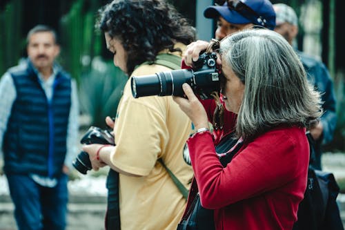 Free A woman taking pictures with a camera in front of people Stock Photo