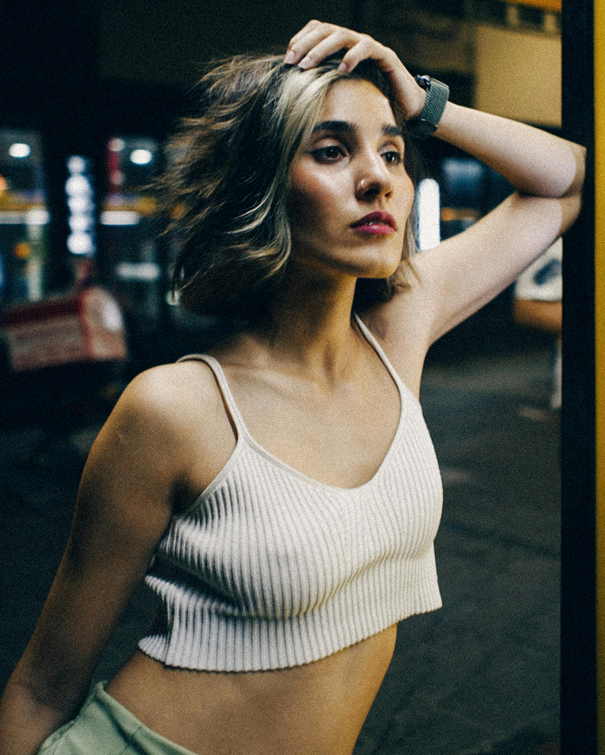 young woman in a crop top posing in city at night