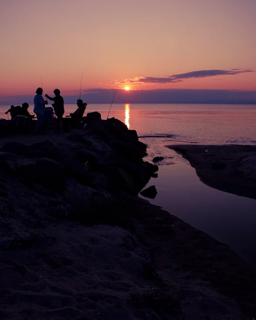 Free Silhouettes of Fishermen on the Seashore at Sunset  Stock Photo