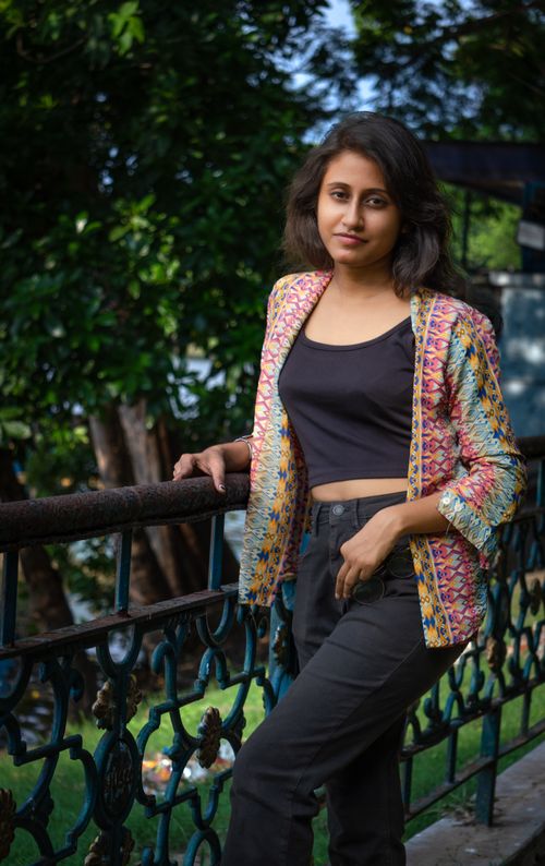 Free A young woman in fashionable attire poses confidently by a decorative railing outdoors. Stock Photo