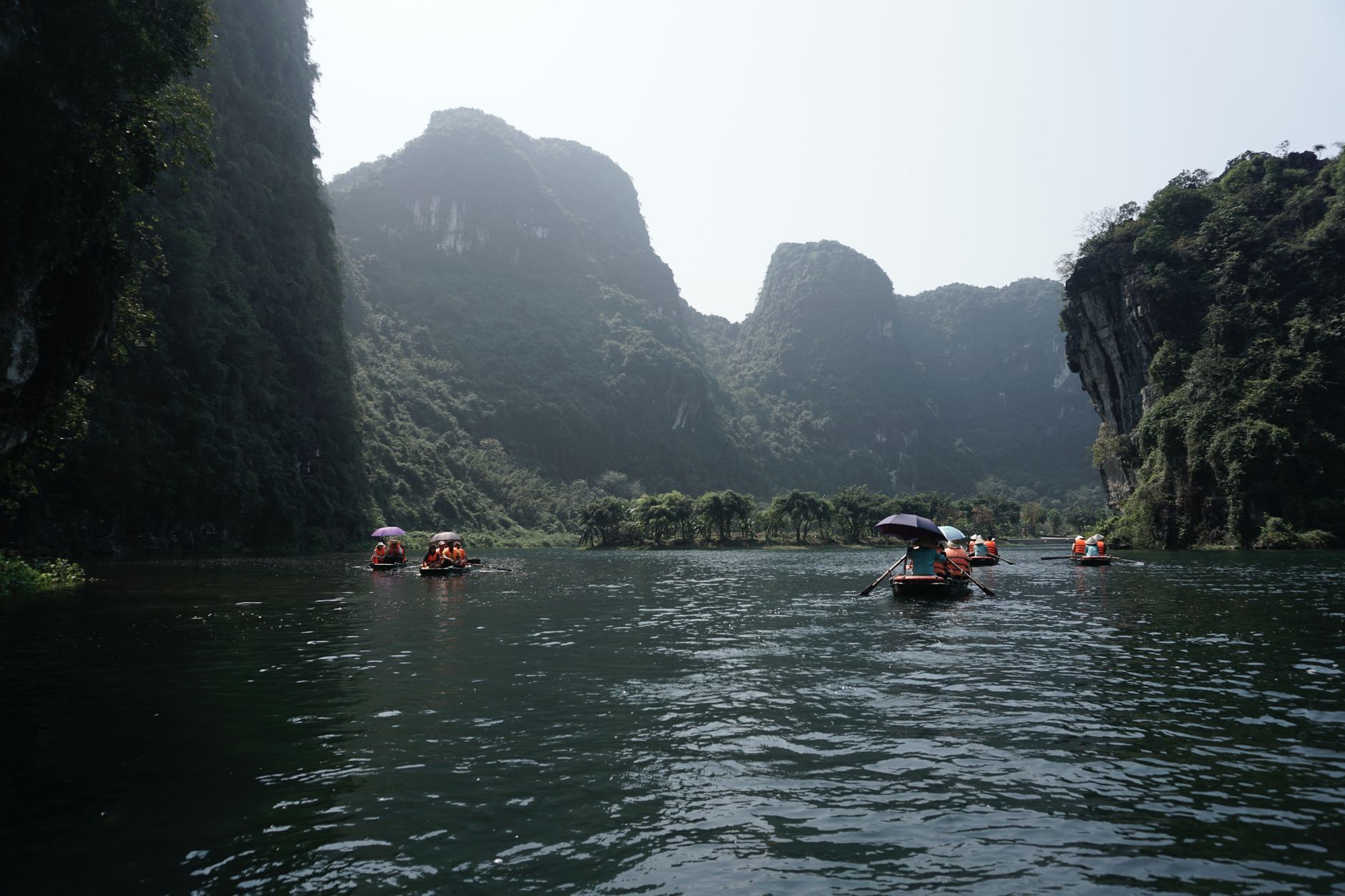 Tourists paddle through stunning limestone cliffs in Ninh Binh, Vietnam, enjoying a peaceful boat ride.