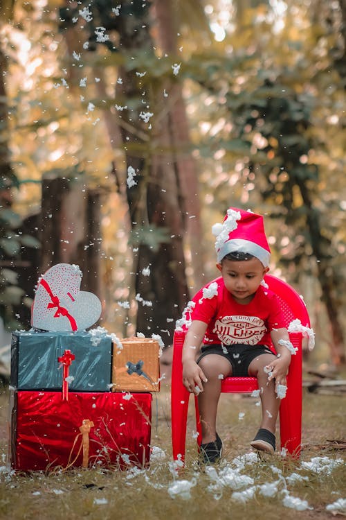 Boy in Santa Hat Sitting near Gifts