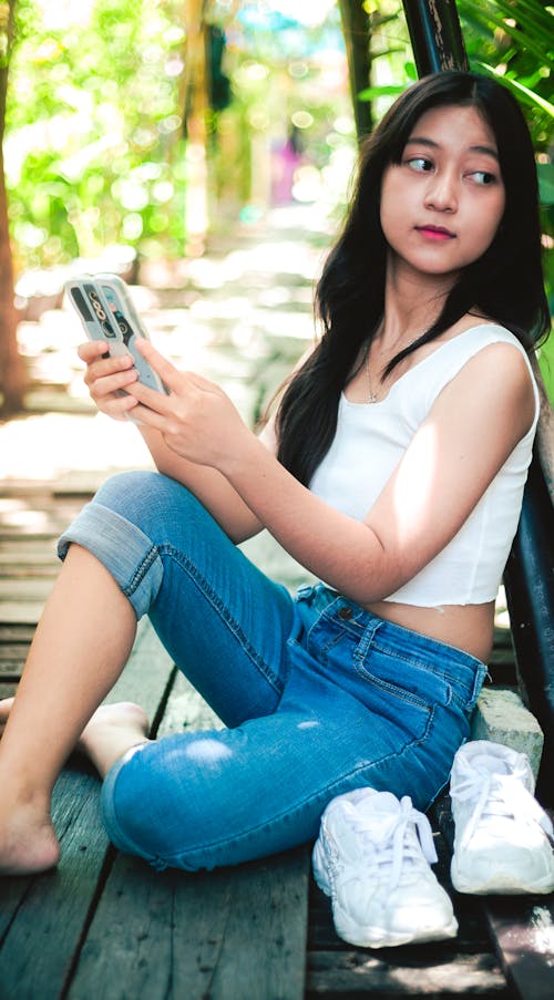 Young Woman Sitting Outside and Holding Her Phone 
