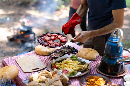 Enjoying an outdoor culinary experience with grilled tomatoes and various side dishes by the campfire.