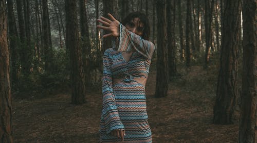 Woman Wearing a Striped Dress, Posing in a Dark Forest