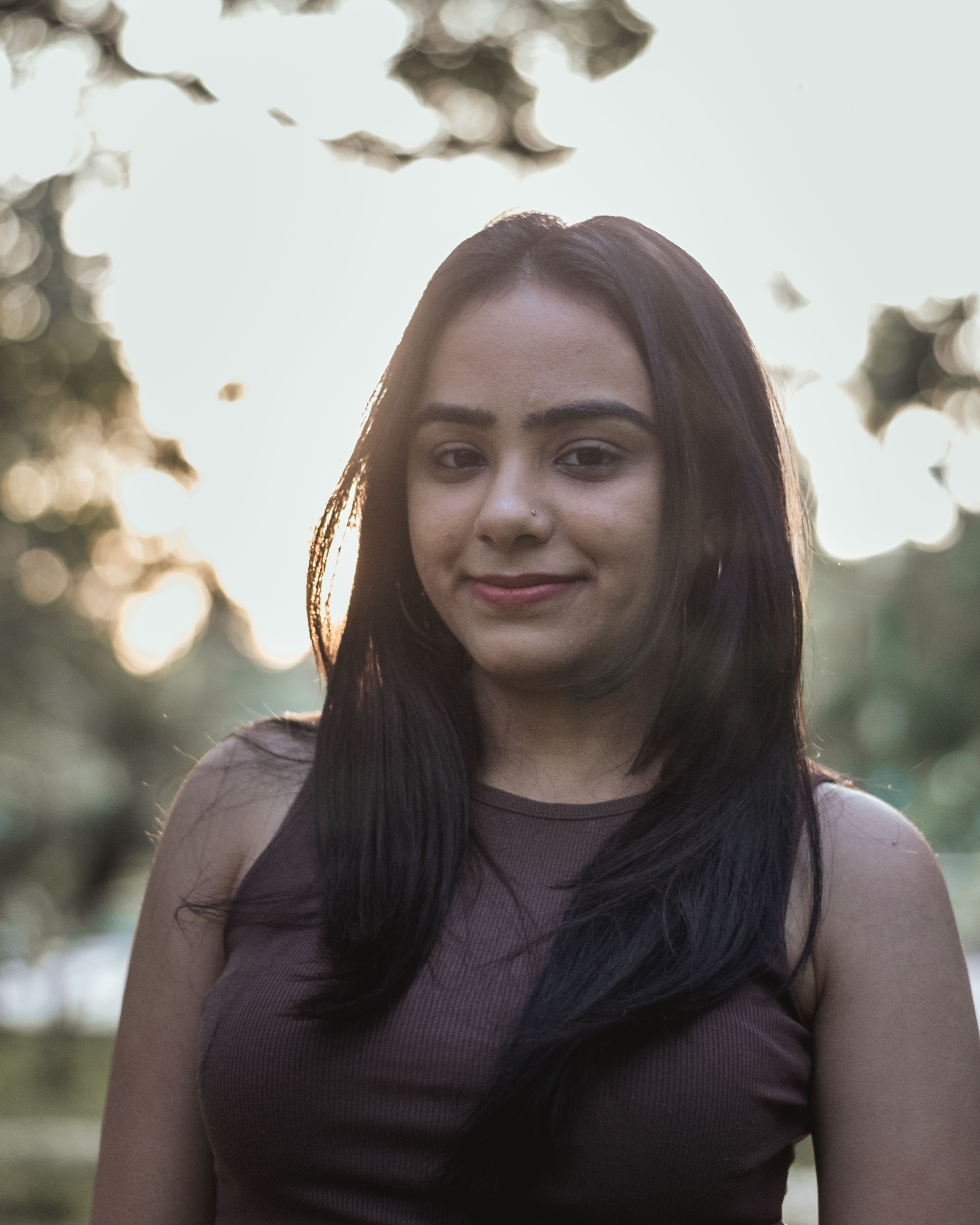 Beautiful portrait of a woman with long hair standing outdoors in warm sunlight.