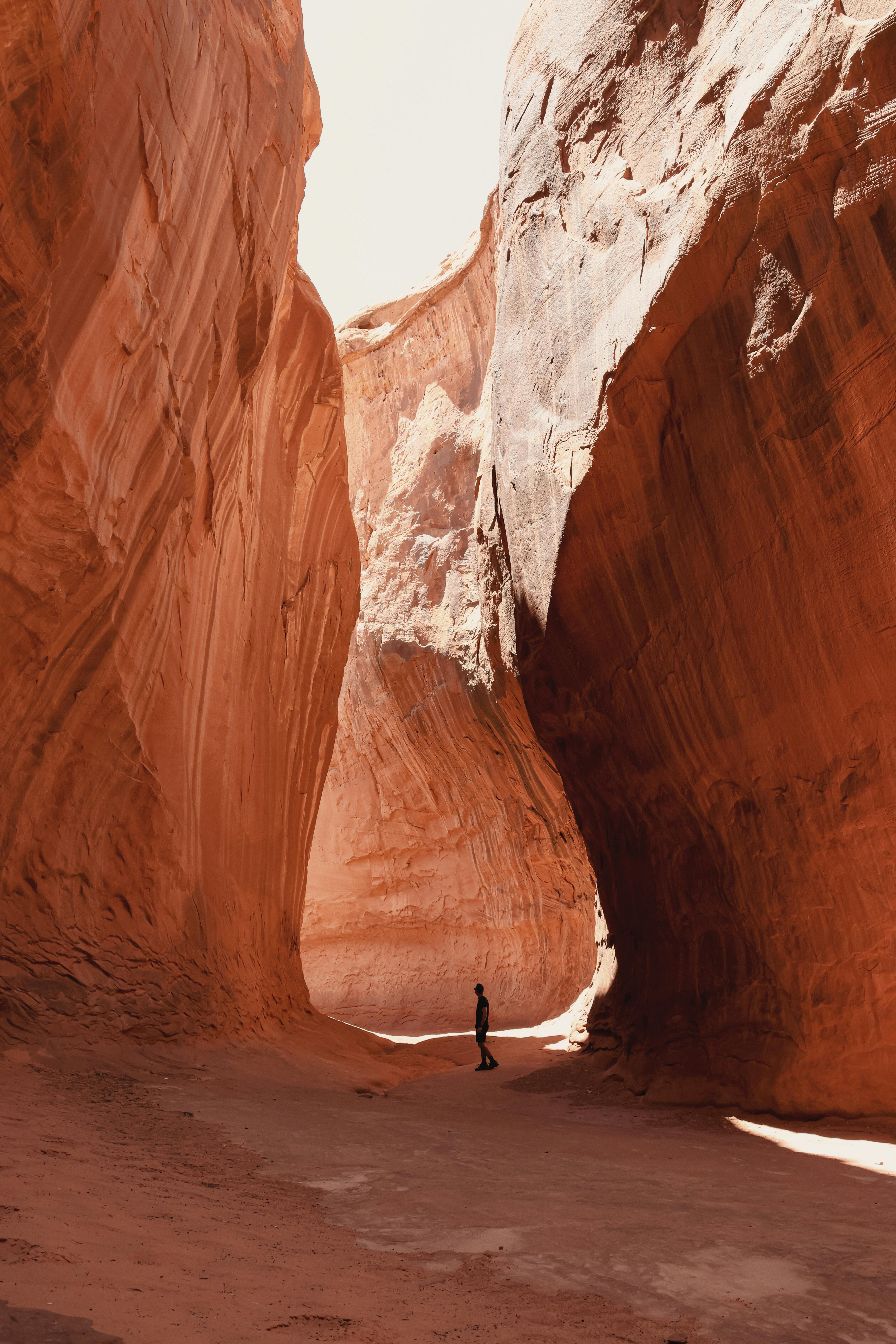 A solitary hiker walks through the stunning rock formations of a canyon near Lake Powell, Utah.