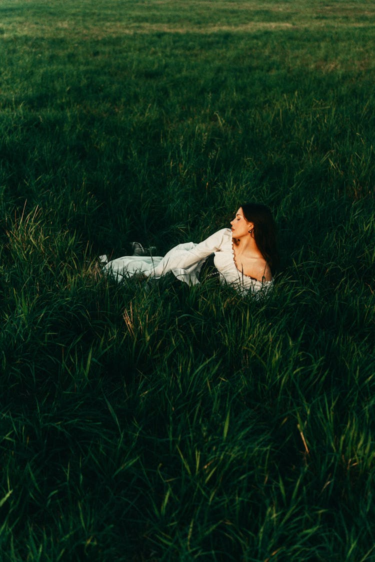 Woman In White Summer Dress Lying In Tall Grass