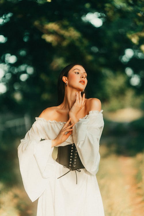 Woman in White Renaissance Dress and Black Corset Posing in a Park