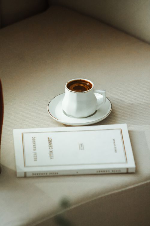 Free A cup of coffee with a book on a minimalist table setting for a calm reading moment. Stock Photo