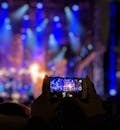 手持智能手机的剪影捕捉到了音乐会充满活力的灯光