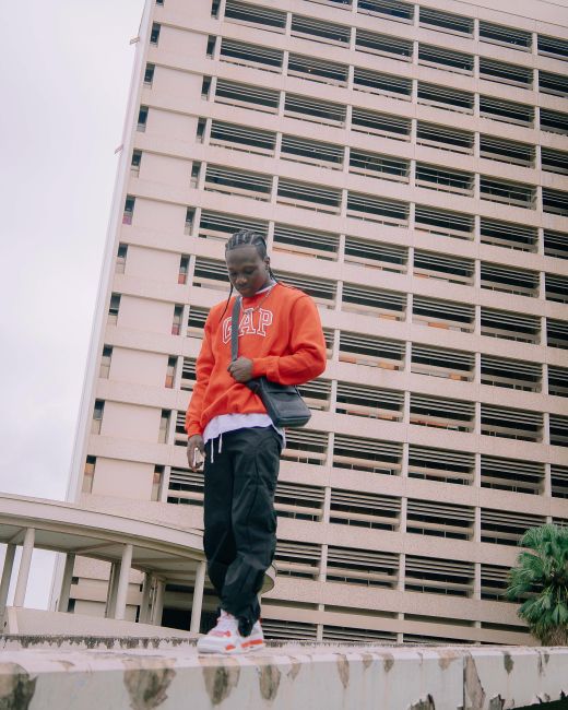 Man in vibrant fashion standing in an urban area, showcasing modern architecture.