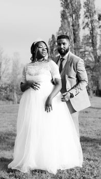 Black and white wedding portrait of a pregnant couple outside.