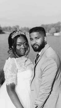 Elegant black and white portrait of a bride and groom by a scenic lakeside, capturing the essence of love.