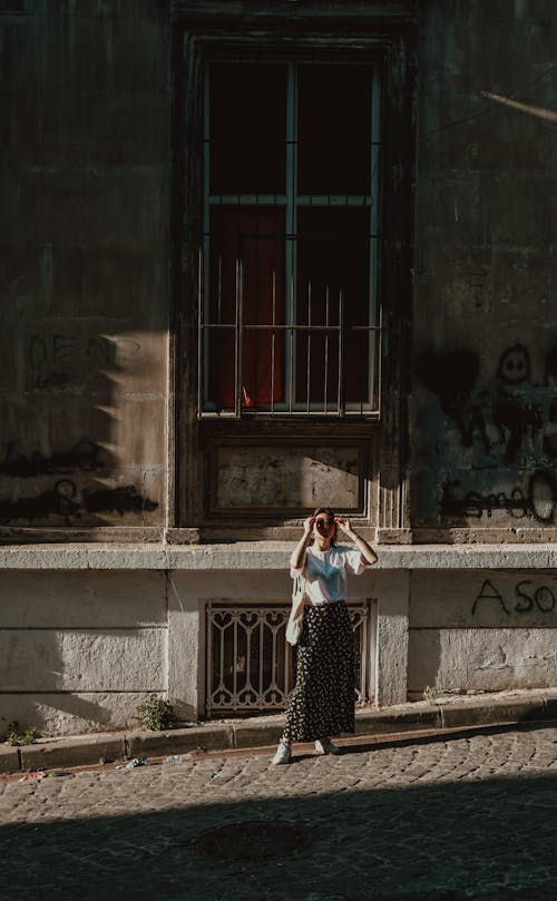 Woman in Skirt Standing on Sunlit, Cobblestone Street
