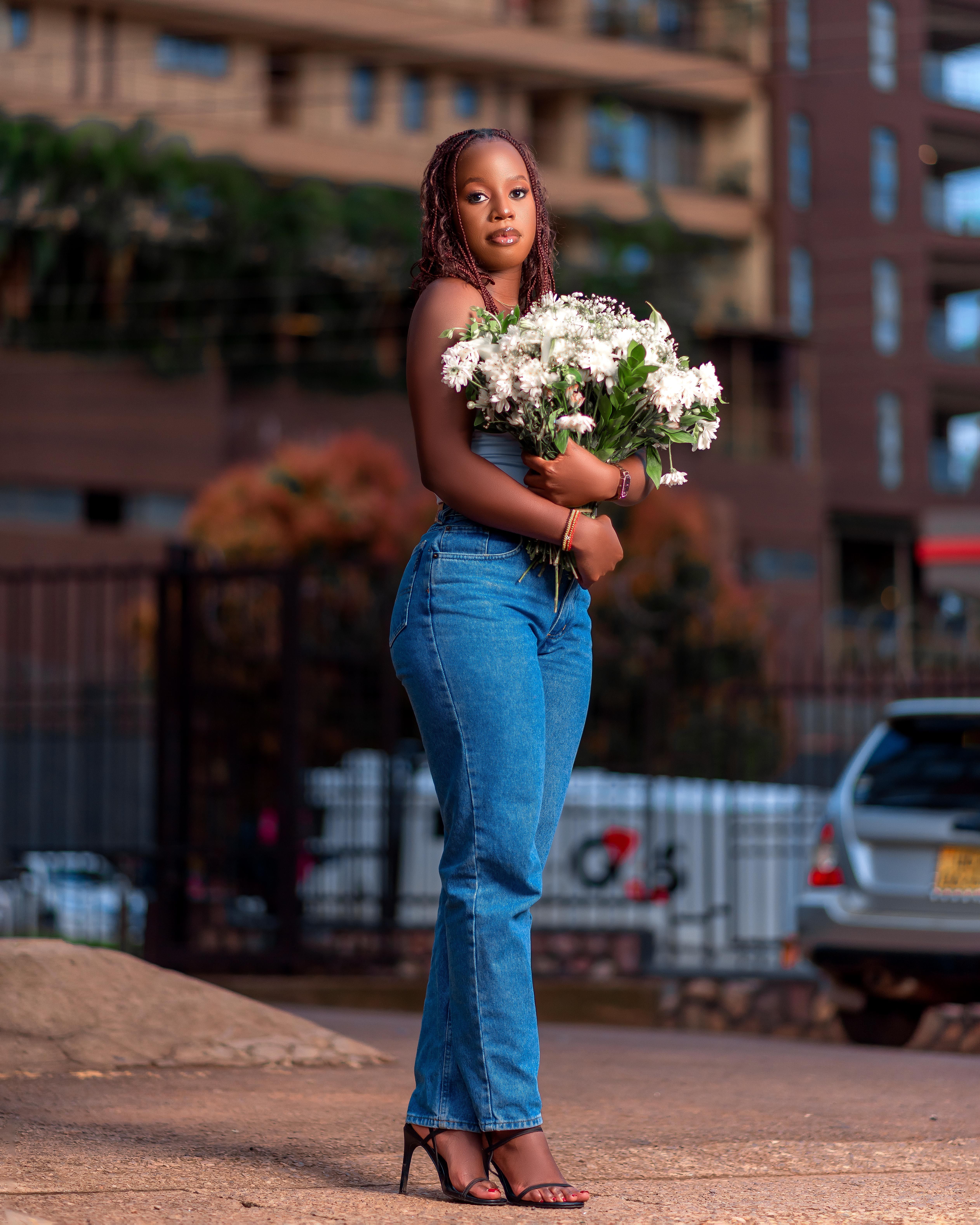 Woman in city street holding a bouquet, showcasing urban fashion.