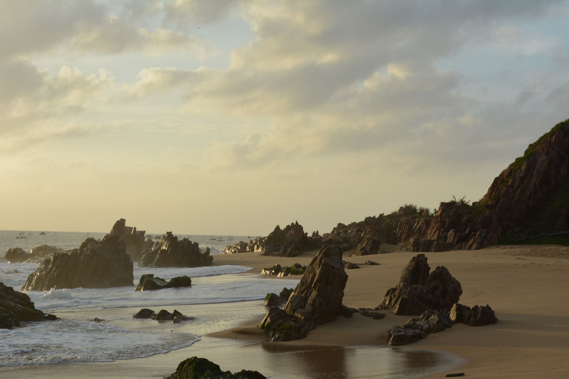 Peaceful beach scene with rocky shoreline at sunset in Quy Nhơn, Vietnam.